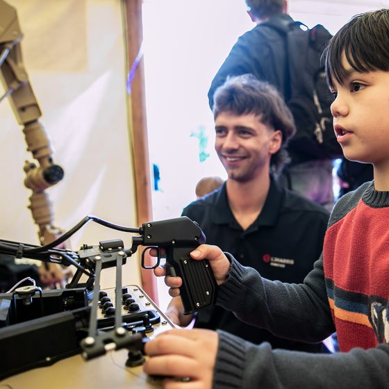 A child uses a machine at Science Festival while an adult watches