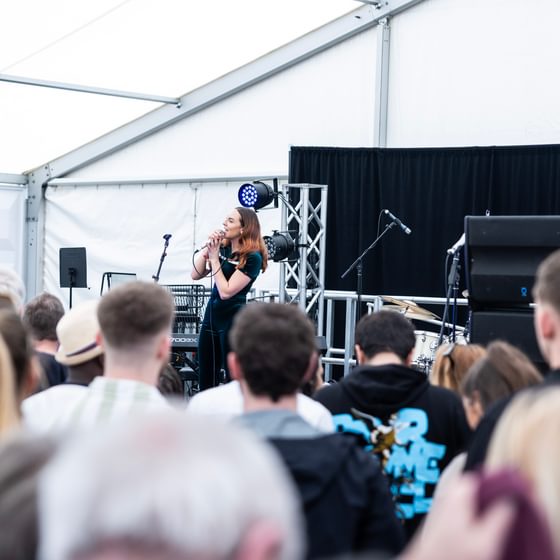 point of view from busy crowd of Immy Odon on stage singing