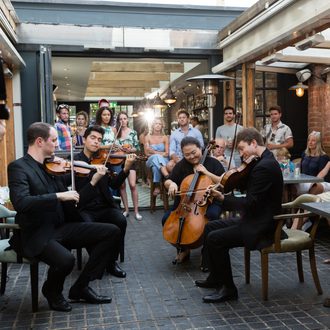 String musicians playing as people look on