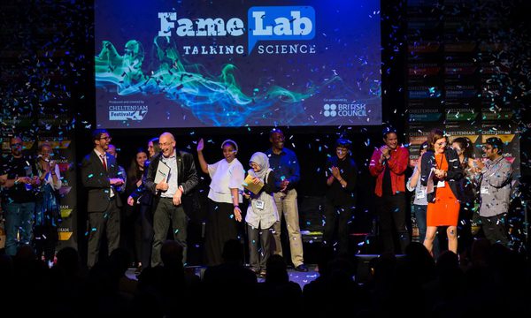 FameLab participants celebrating on stage in front of a screen that reads 'FameLab Talking Science'