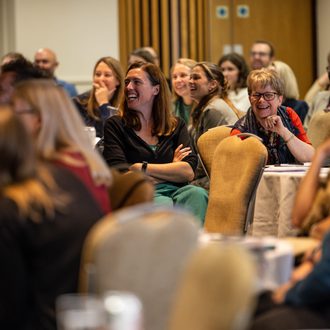 Teachers smiling and laughing in a room at RTRP conference