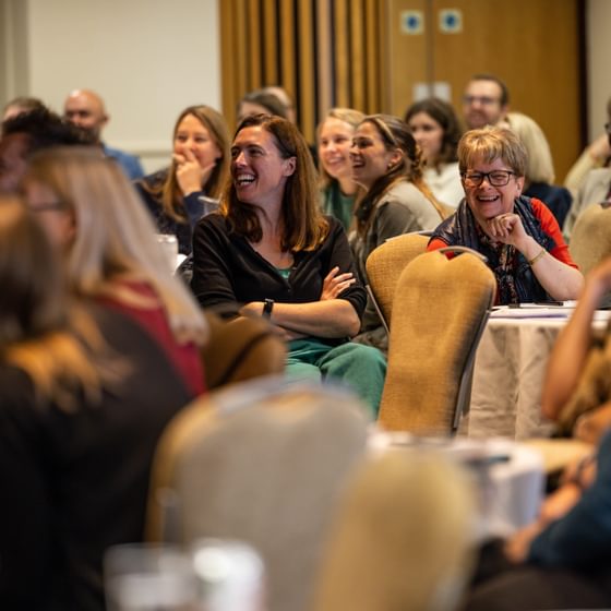 Teachers smiling and laughing in a room at RTRP conference