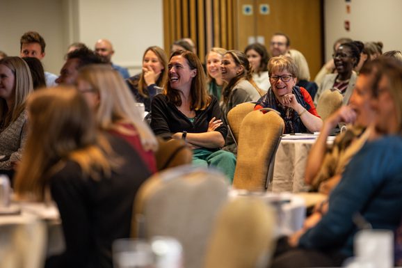 Teachers smiling and laughing in a room at RTRP conference