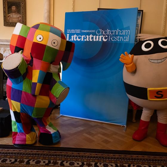 Two mascots by banner