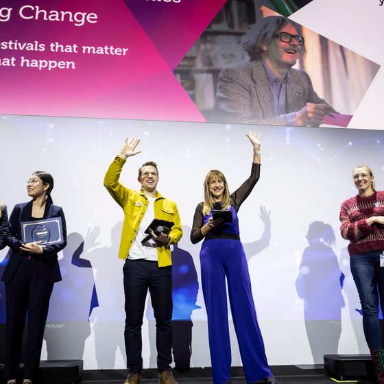Host Greg Foot on-stage with FameLab International 2025 finalists