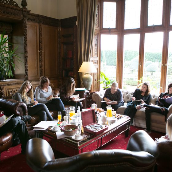 A group sit around a table in a large room writing
