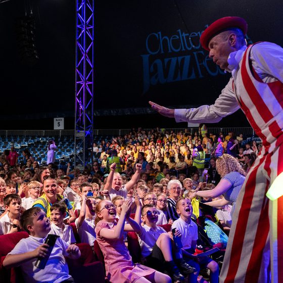 A shot from the stage of the audience at Jazz Concert for Schools 2025 with a stilt walker in shot