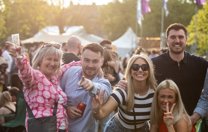 group of festival-goers pointing and smiling at camera