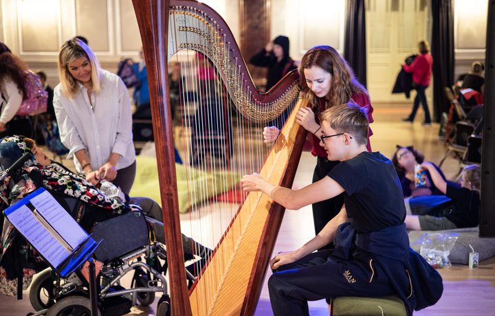 A harpist shows students how to play at Relaxed Concert for Schools at Cheltenham Music Festival