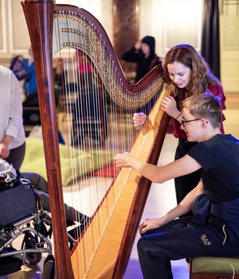 A harpist shows students how to play at Relaxed Concert for Schools at Cheltenham Music Festival