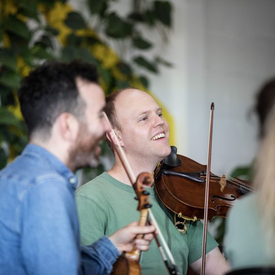 A man smiling while playing the violin