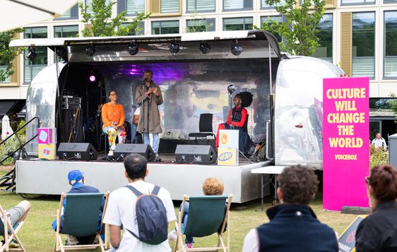 Speakers on the Jetstream stage with the backs of Festival-goers sitting in the audience