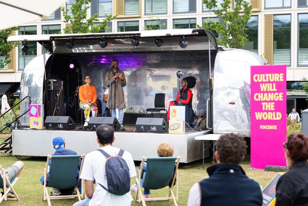 Speakers on the Jetstream stage with the backs of Festival-goers sitting in the audience