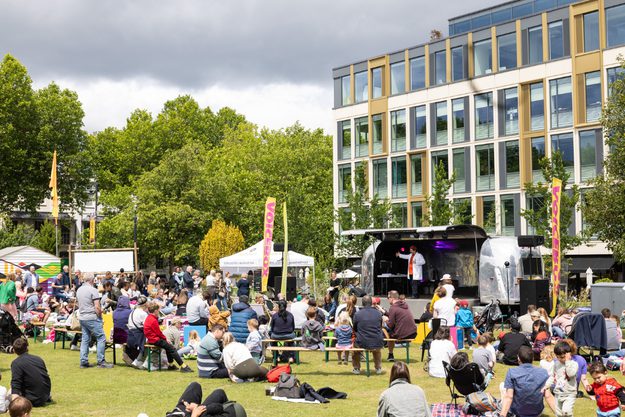 A busy Festival site with Festival-goers sat around the grass in front of the Jetstream venue