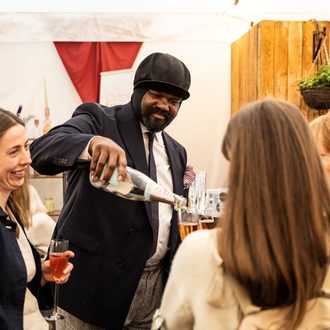 Gregory Porter pouring champagne into glass with patrons