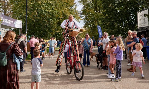 Man on stilts riding bike through crowd