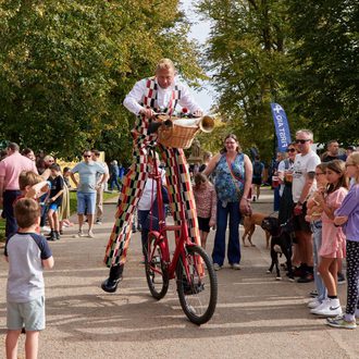 Man on stilts riding bike through crowd