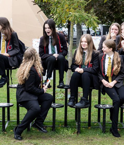 A group of 9 school children sitting on a giant typewriter at Cheltenham Literature Festival.