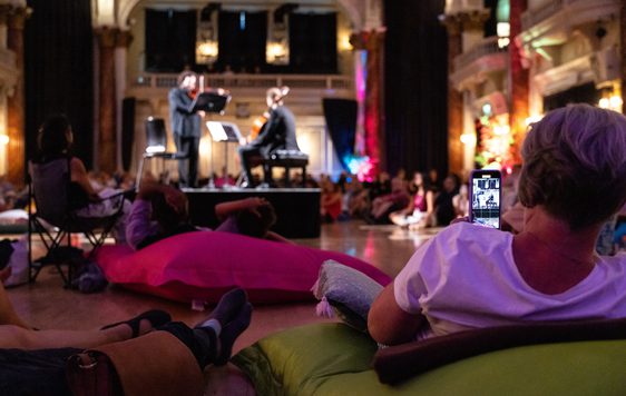 A personal led back on a beanbag watching artists plau instruments on stage