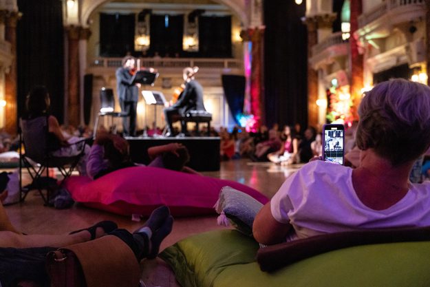 A personal led back on a beanbag watching artists plau instruments on stage