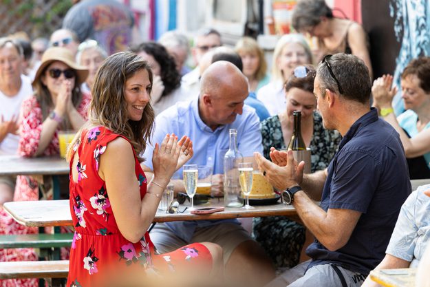 People sat on picnic benches clapping after hearing music