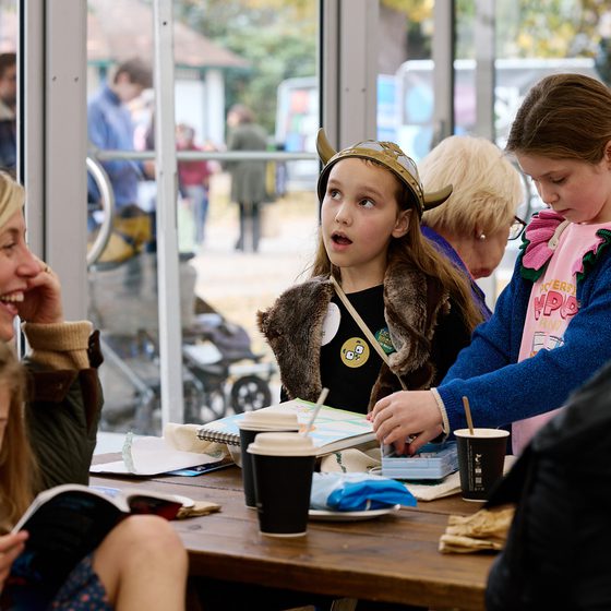 A mother smiling with her three children sat in the Feast Cafe. One of them is reading.
