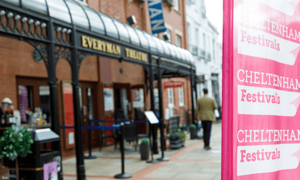 The outside of the Everyman Theatre out of focus behind a pink Cheltenham Festivals banner.