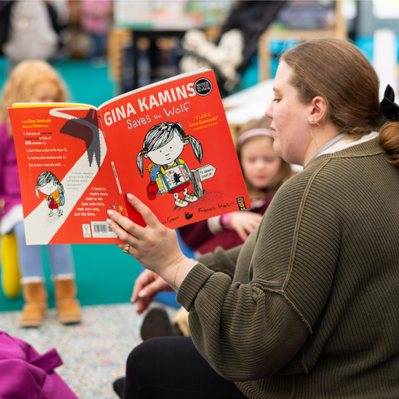 A woman reading a picture book to children