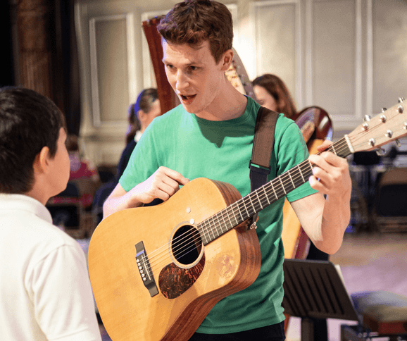 Man with guitar teaching pupil at Musicate