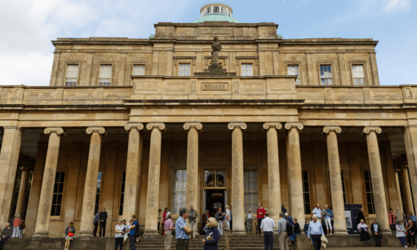 The outside of Pittville Pump Rooms with people milling about in front of it.