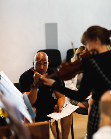 Person playing violin while course director looks on
